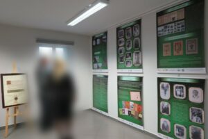 Plakat zapraszający na wystawę a na przeciw plakatu widać 6 plansz wystawy